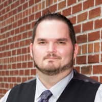 A person standing in front of a brick wall in business attire